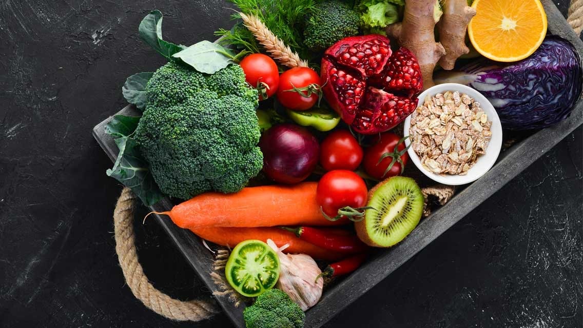 A tray of colourful whole-food ingredients - broccoli, pomegranate, carrots and ginger