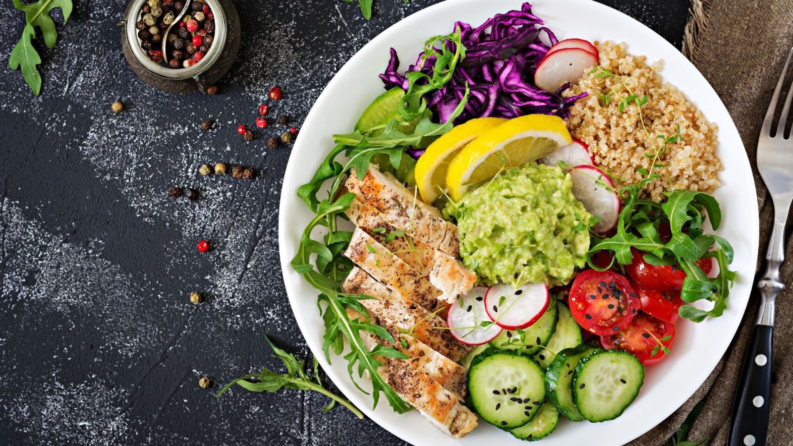 A balanced bowl with grilled chicken, quinoa, guacamole and fresh vegetables