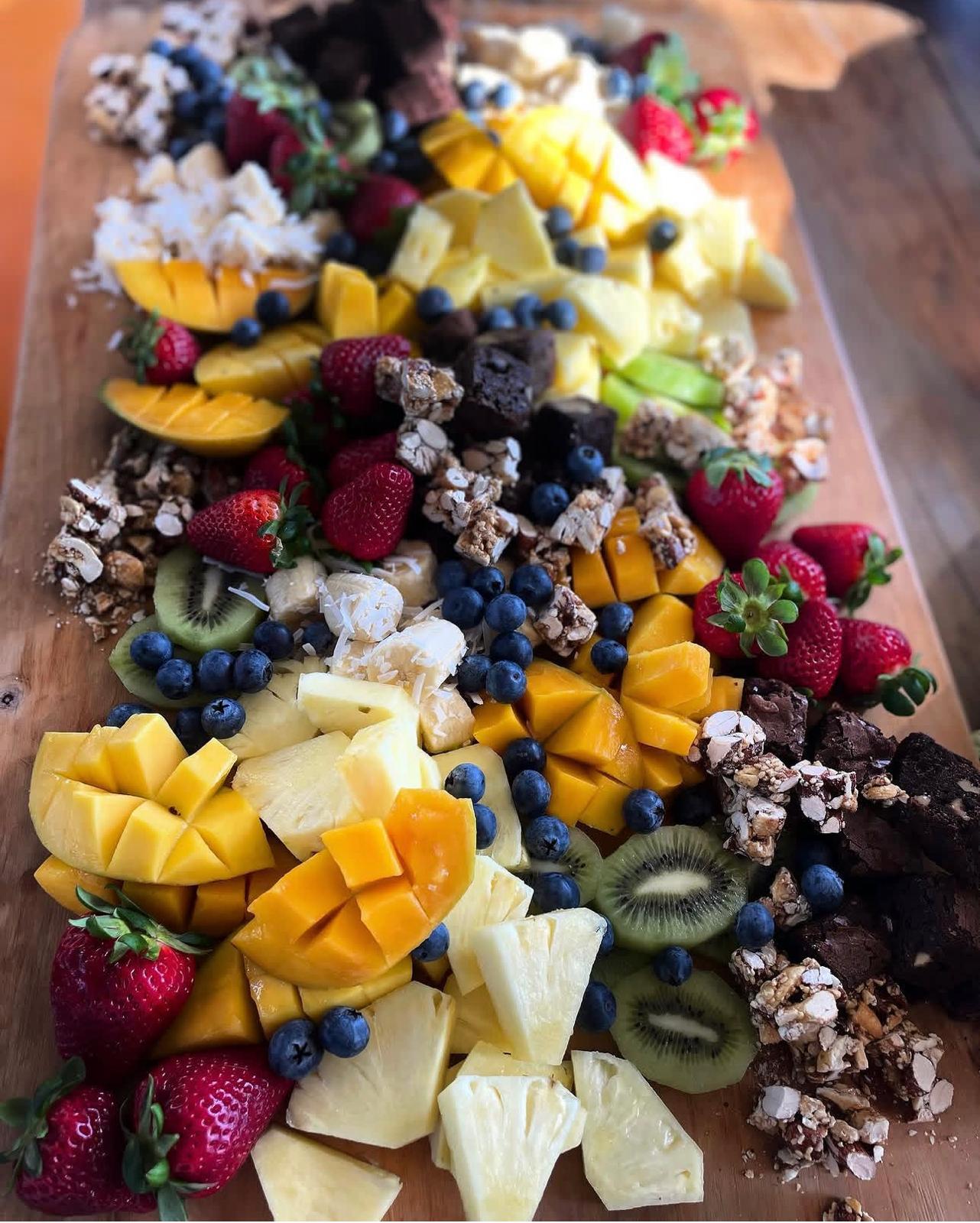 A grazing board of fresh mango, pineapple, strawberries, blueberries and kiwi