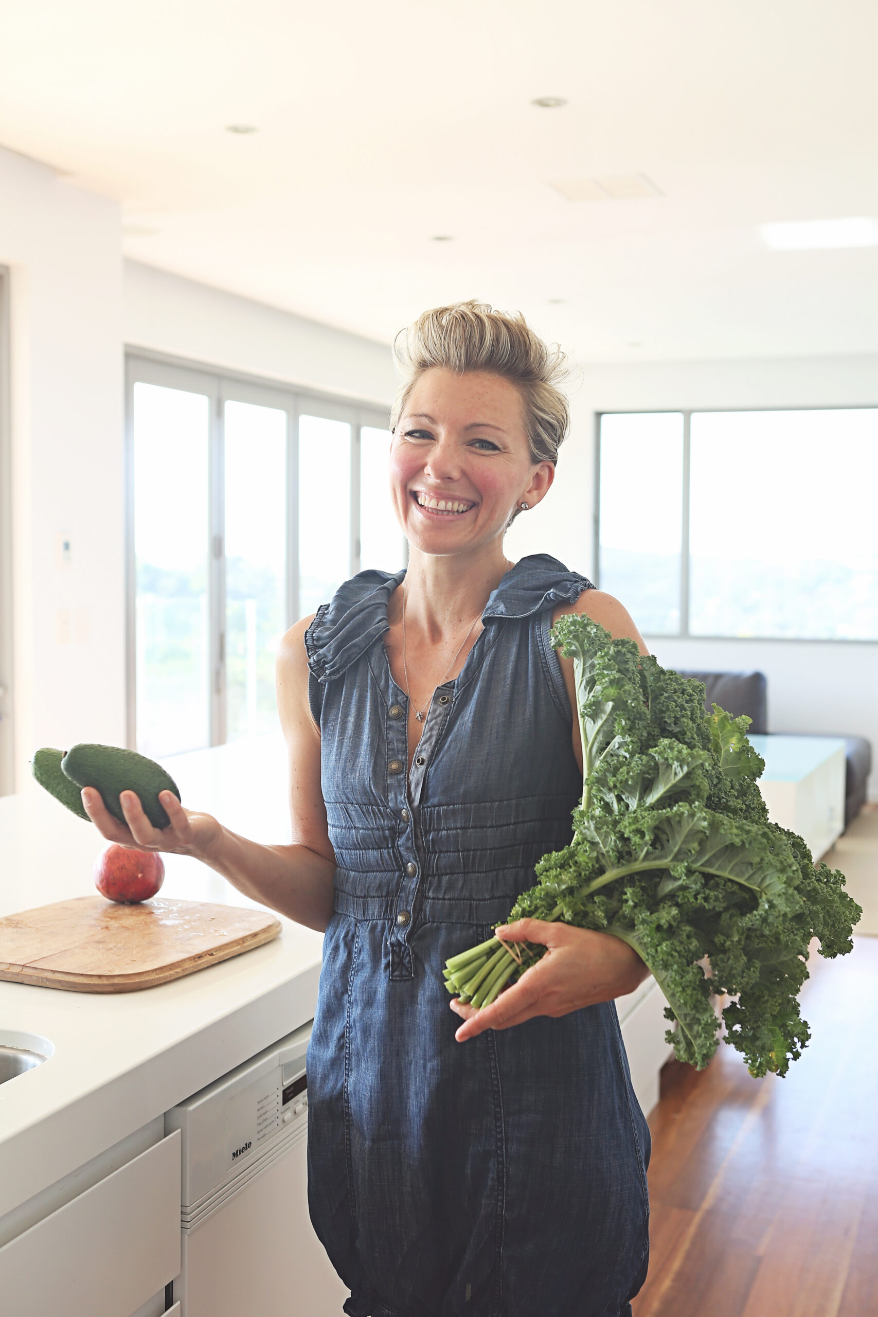 Rebekah Raymond in her kitchen, holding fresh kale and avocado